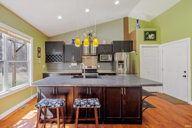 kitchen featuring light wood finished floors, visible vents, a breakfast bar area, appliances with stainless steel finishes, and a sink