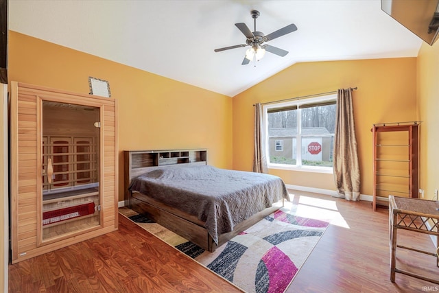 bedroom with ceiling fan, wood finished floors, baseboards, and vaulted ceiling