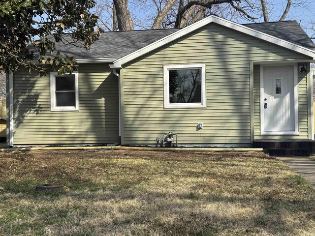 view of front facade featuring roof with shingles and a front lawn