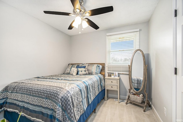 bedroom with light colored carpet, a ceiling fan, and baseboards