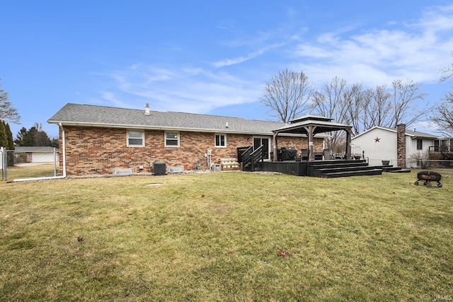 rear view of house with a gazebo, a yard, brick siding, and fence