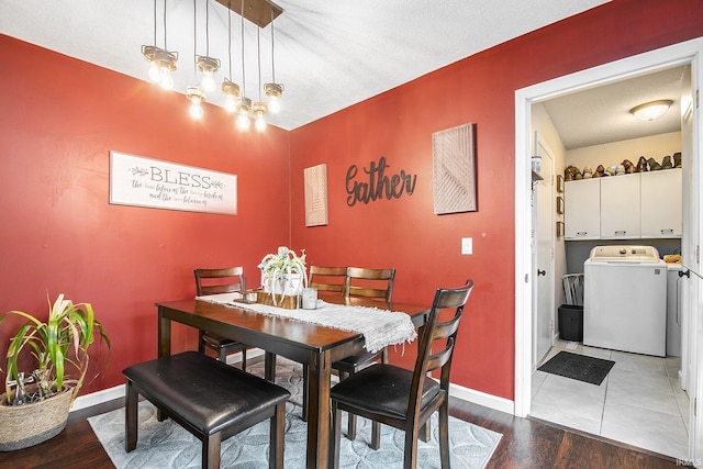 dining space featuring baseboards, a textured ceiling, wood finished floors, and washing machine and clothes dryer