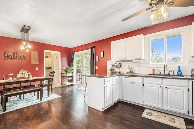 kitchen featuring a ceiling fan, a sink, a peninsula, dishwasher, and dark wood-style flooring