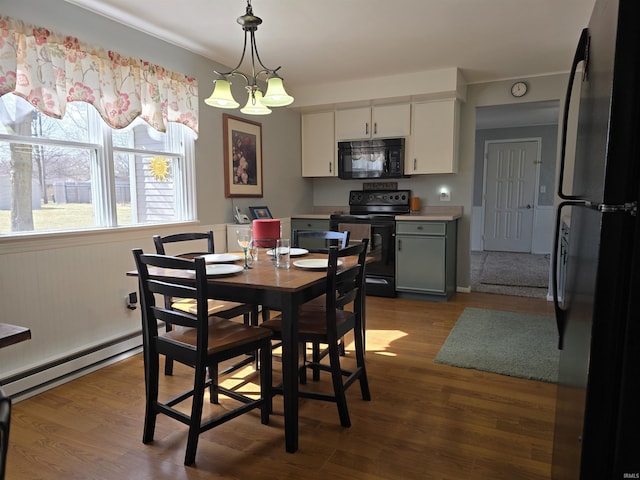 dining space with wood finished floors, baseboard heating, and a chandelier