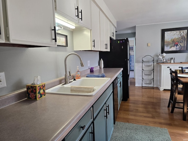 kitchen with dark wood-style floors, a sink, light countertops, white cabinets, and black dishwasher