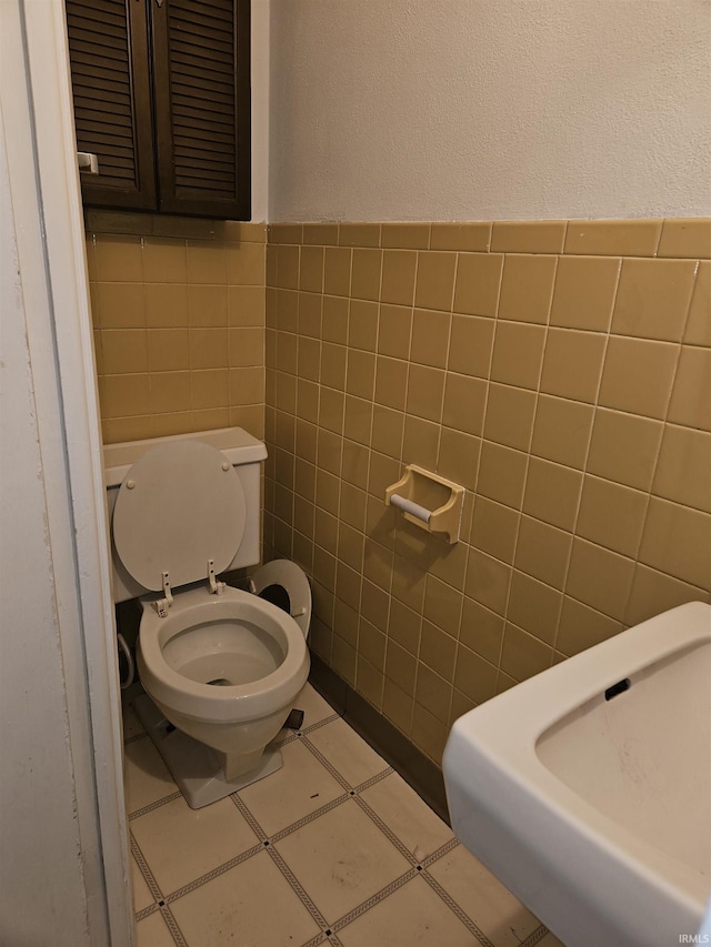 bathroom featuring tile walls, toilet, a wainscoted wall, and a textured wall