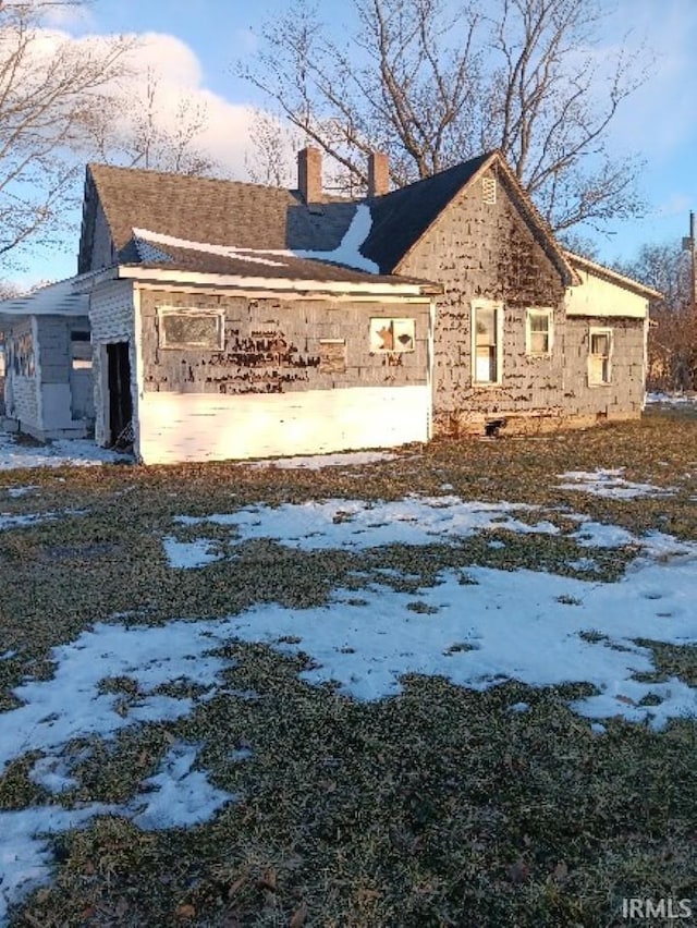 snow covered property with a chimney