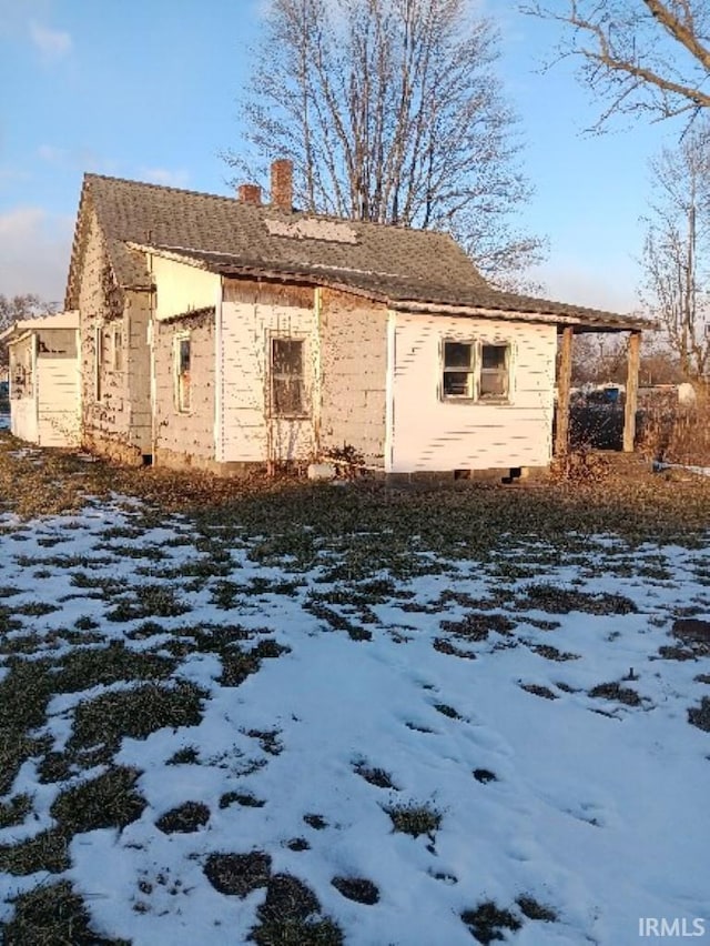 view of snow covered exterior featuring a chimney