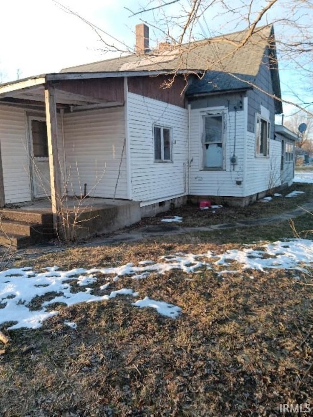 view of property exterior with crawl space and a chimney