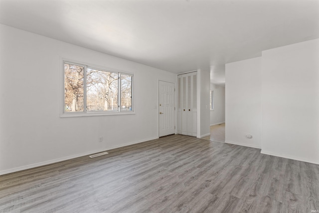 empty room with baseboards, visible vents, and light wood-type flooring