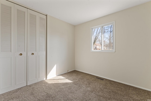 unfurnished bedroom featuring carpet, visible vents, a closet, and baseboards