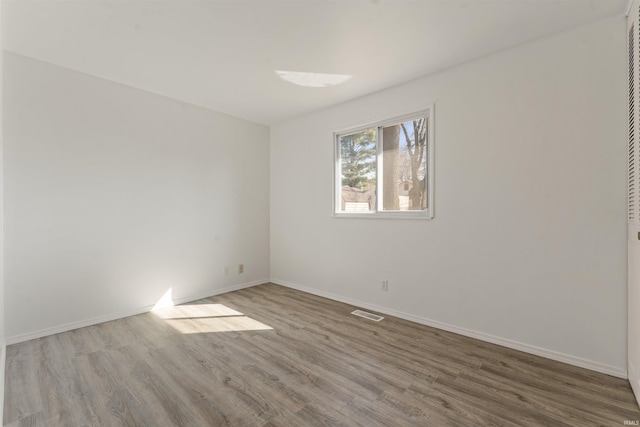 spare room featuring visible vents, wood finished floors, and baseboards