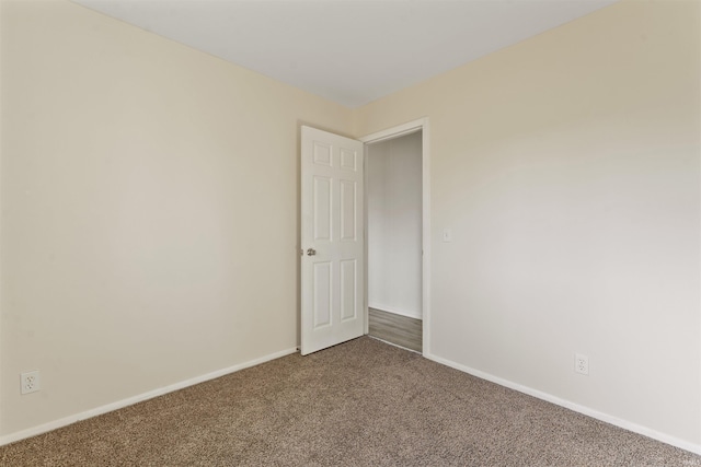 carpeted empty room featuring baseboards