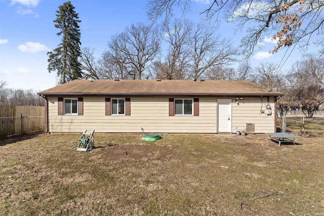 back of house with a yard, a shingled roof, and fence