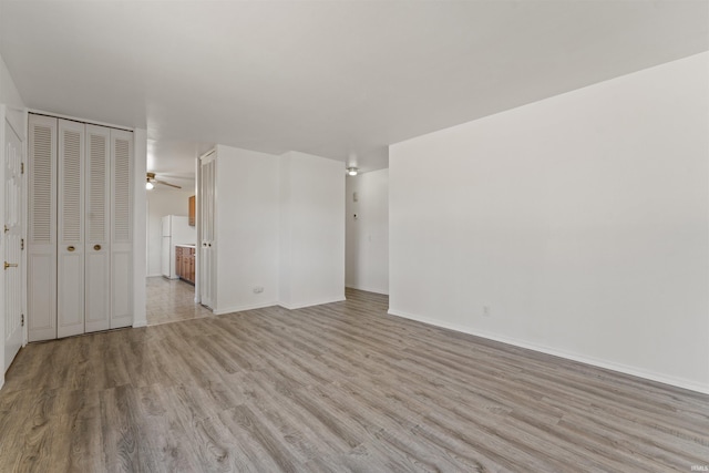 interior space with baseboards, light wood-style floors, and ceiling fan