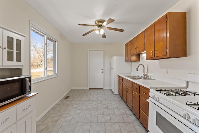 kitchen with a sink, white appliances, a ceiling fan, and brown cabinetry