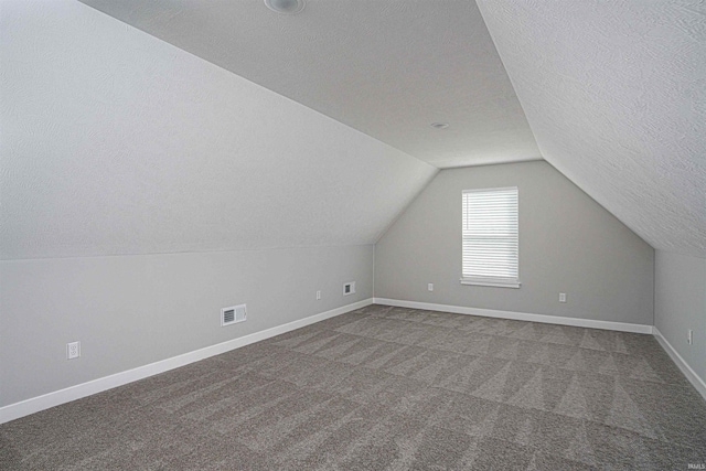 19138 Braeburn Dr, Evansville, IN 47725 - additional living space with visible vents, baseboards, vaulted ceiling, carpet floors, and a textured ceiling