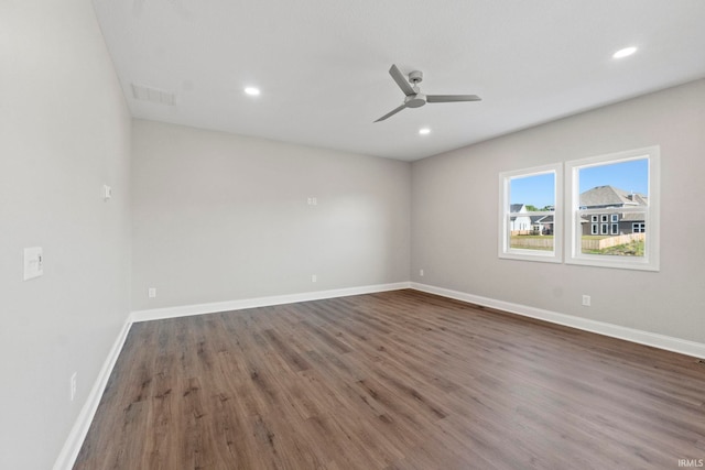 empty room with wood finished floors, baseboards, visible vents, and ceiling fan
