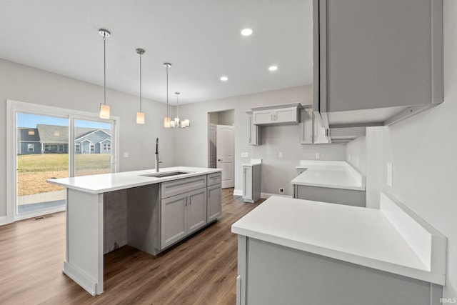 kitchen with a center island with sink, recessed lighting, gray cabinets, wood finished floors, and a sink