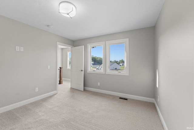 unfurnished room with visible vents, light carpet, and baseboards