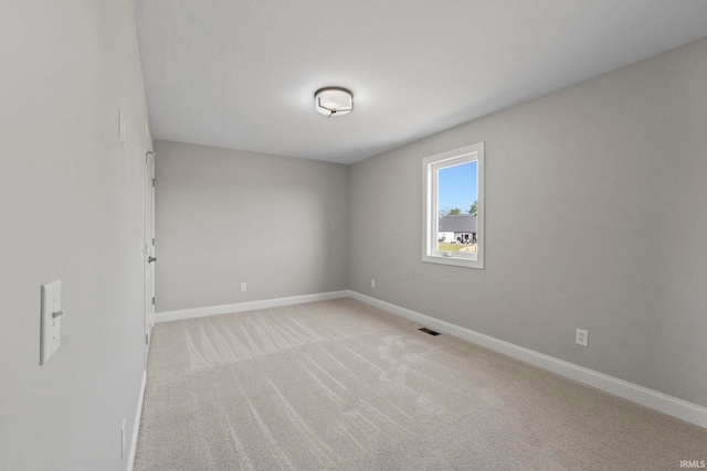 spare room with visible vents, light colored carpet, and baseboards