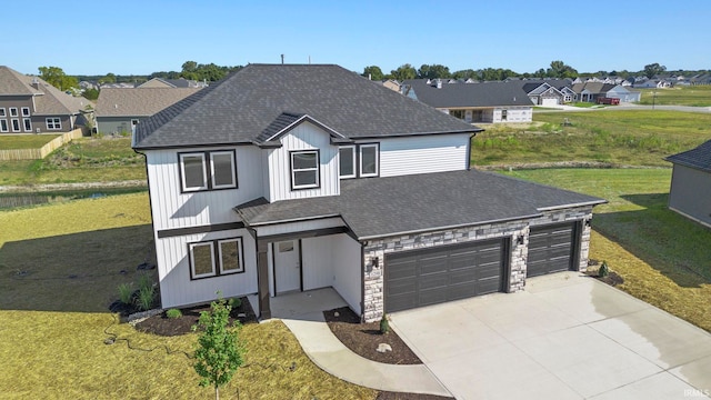 view of front of house with a garage, concrete driveway, a front yard, and a shingled roof