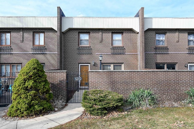 exterior space with a gate, brick siding, and fence