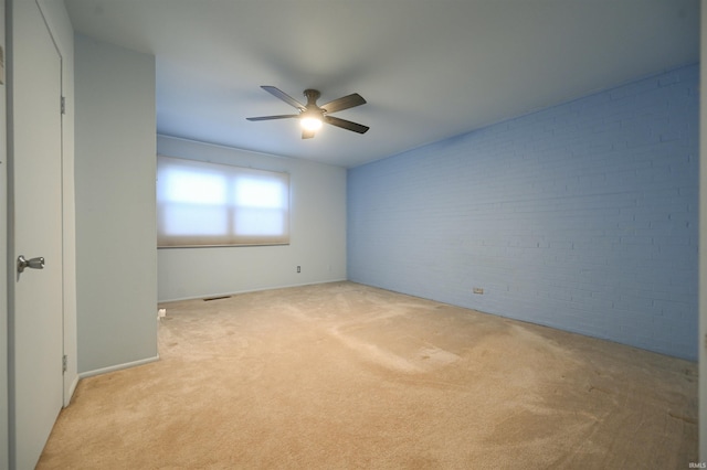 unfurnished room with ceiling fan, brick wall, and light carpet