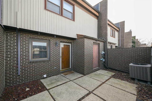 back of house featuring brick siding and central AC
