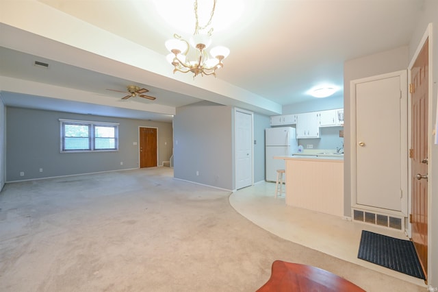 unfurnished living room with visible vents, light carpet, baseboards, and ceiling fan with notable chandelier