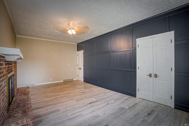 9700 Big Cynthiana Rd, Evansville, IN 47720 - unfurnished living room with visible vents, ornamental molding, a fireplace, wood finished floors, and a decorative wall
