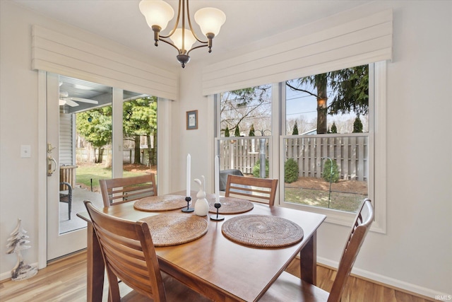 dining space with light wood finished floors, a chandelier, and baseboards