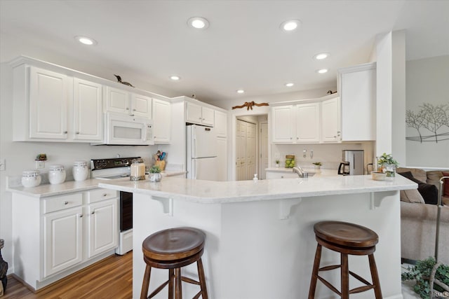 kitchen with white appliances, a kitchen breakfast bar, a peninsula, and light wood finished floors