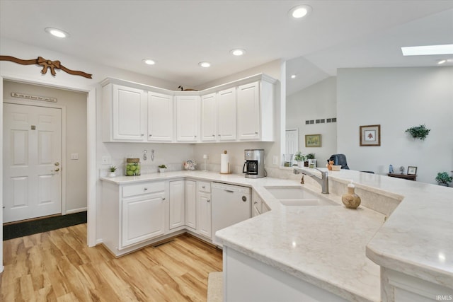 kitchen with a sink, a peninsula, white cabinets, and white dishwasher