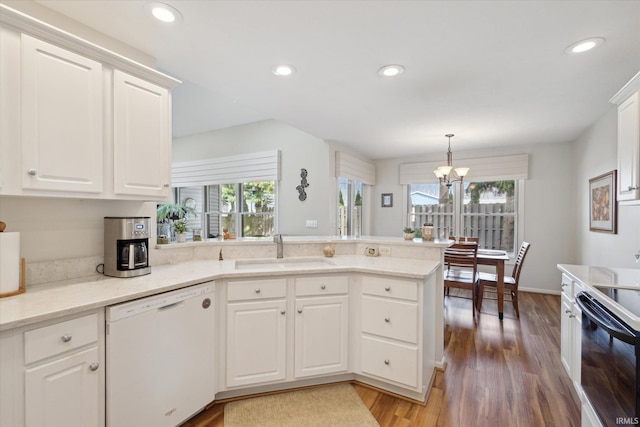 kitchen with a sink, white cabinetry, a peninsula, dishwasher, and a chandelier