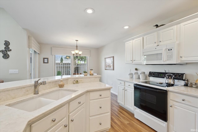 kitchen with white microwave, an inviting chandelier, light wood-style flooring, a sink, and range with electric stovetop