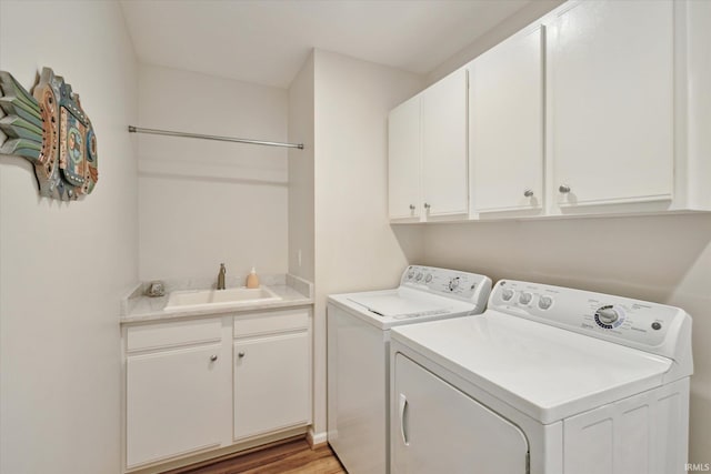 laundry room featuring washing machine and clothes dryer, cabinet space, light wood-type flooring, and a sink