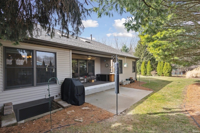 back of house with a patio, a lawn, and a shingled roof