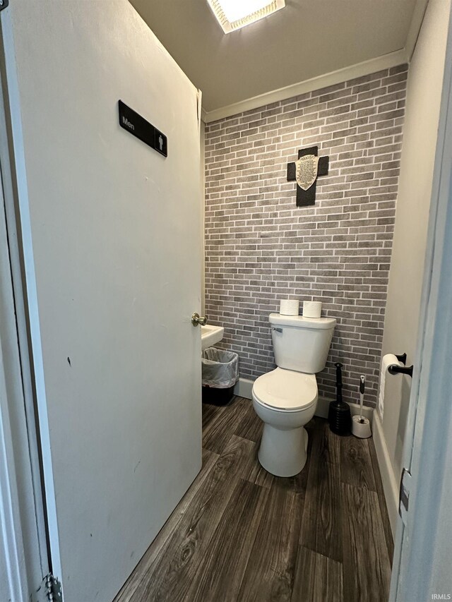 316 N Main St, Churubusco, IN 46723 - bathroom with crown molding, toilet, wood finished floors, and brick wall