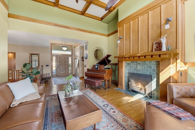 living area with beam ceiling, light wood-style flooring, a fireplace, a high ceiling, and coffered ceiling