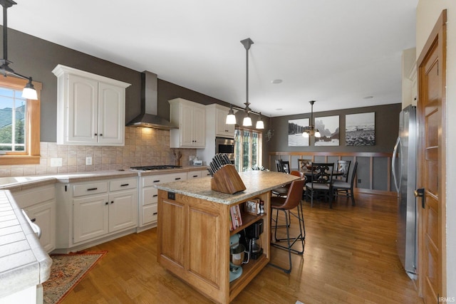 kitchen with open shelves, white cabinetry, freestanding refrigerator, and wall chimney range hood