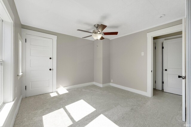 unfurnished bedroom featuring light carpet, a ceiling fan, and baseboards