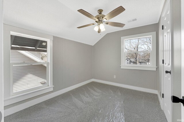 interior space featuring visible vents, baseboards, vaulted ceiling, carpet flooring, and a ceiling fan