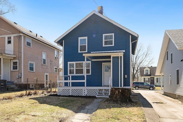 view of front facade with a porch, a chimney, and a front yard