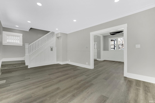 unfurnished living room with plenty of natural light, stairs, baseboards, and wood finished floors