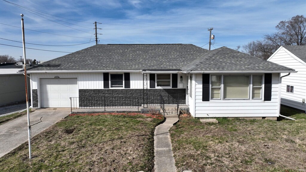 view of front facade featuring concrete driveway, a front lawn, a garage, and a shingled roof