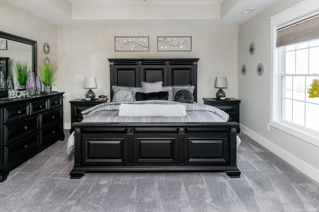 bedroom with a tray ceiling, baseboards, and carpet floors