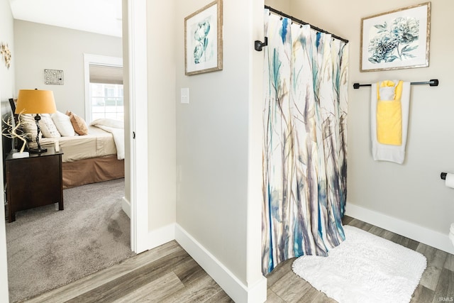 full bathroom featuring connected bathroom, a shower with shower curtain, baseboards, and wood finished floors