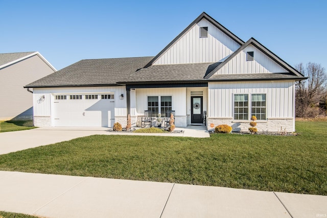 view of front of property featuring a front yard, concrete driveway, a garage, and stone siding