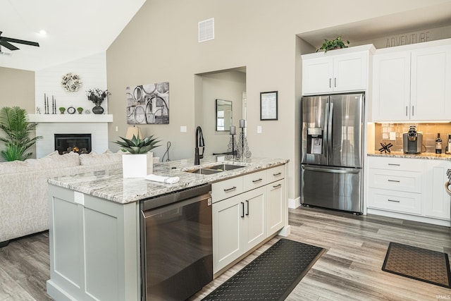 kitchen featuring visible vents, a sink, open floor plan, appliances with stainless steel finishes, and lofted ceiling